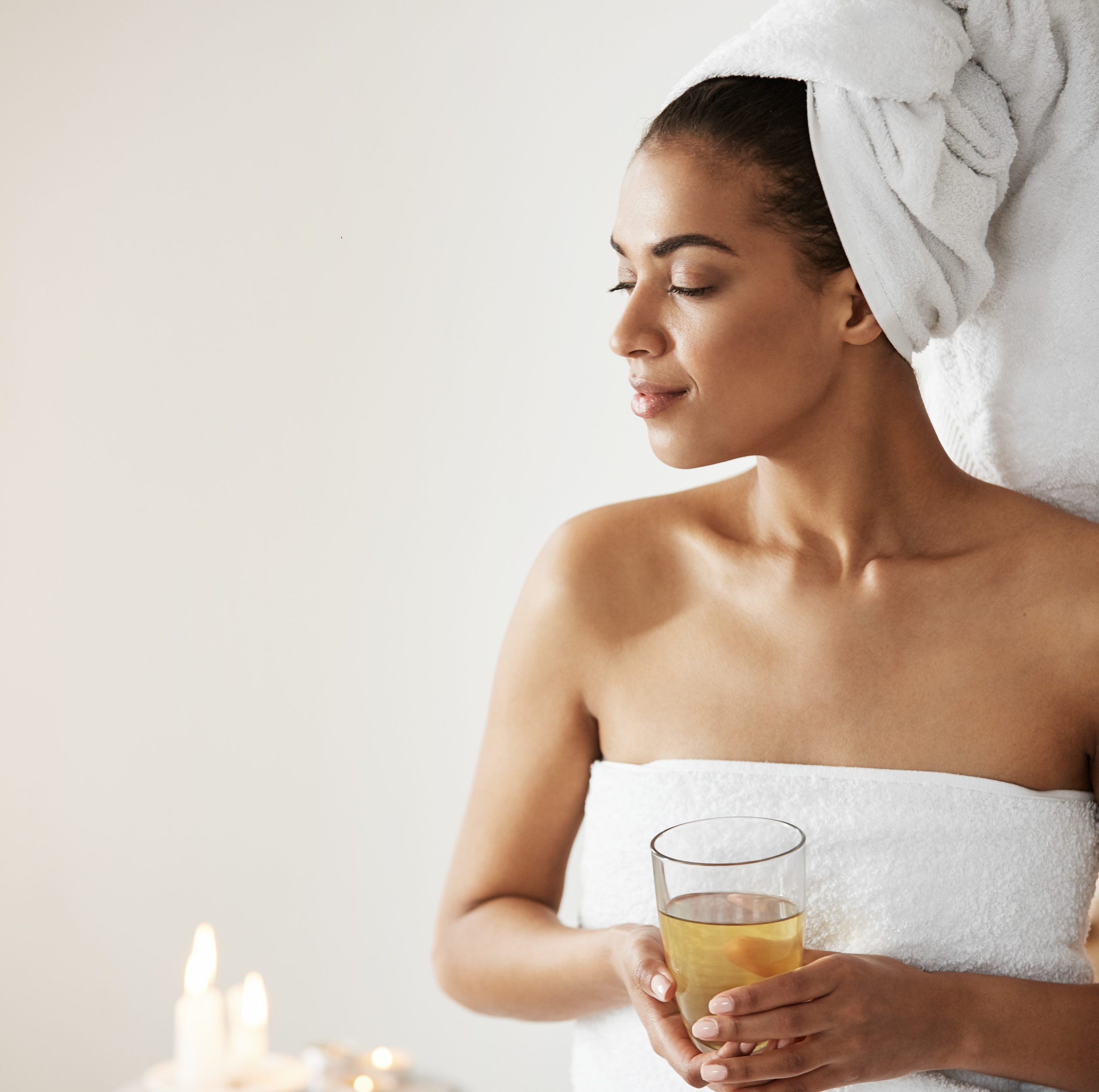 african woman with towel head holding glass smiling looking side resting spa resort scaled